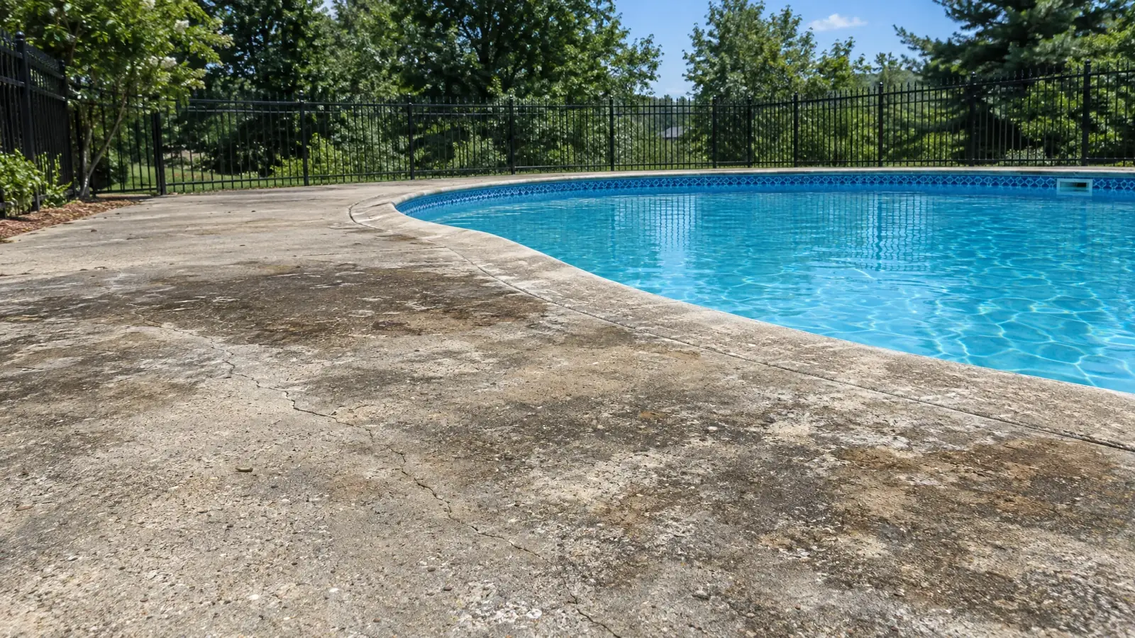 Pool deck with worn, stained bare concrete before coating